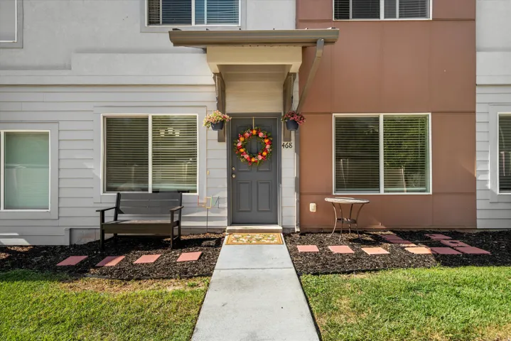 Modern townhouse exterior featuring a gray paneled entry door, contrasting brown and light gray siding, and a concrete pathway