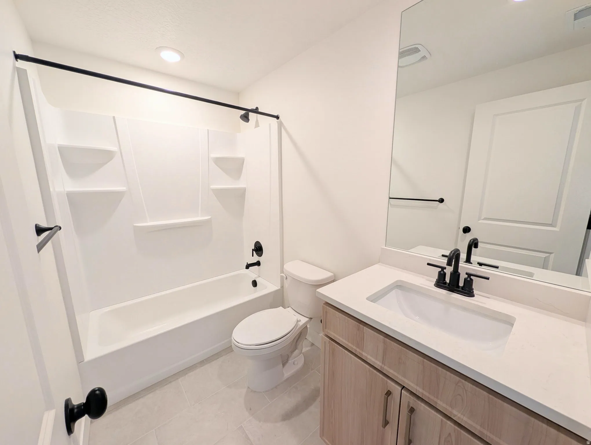 White bathtub with integrated shelving and matte black fixtures