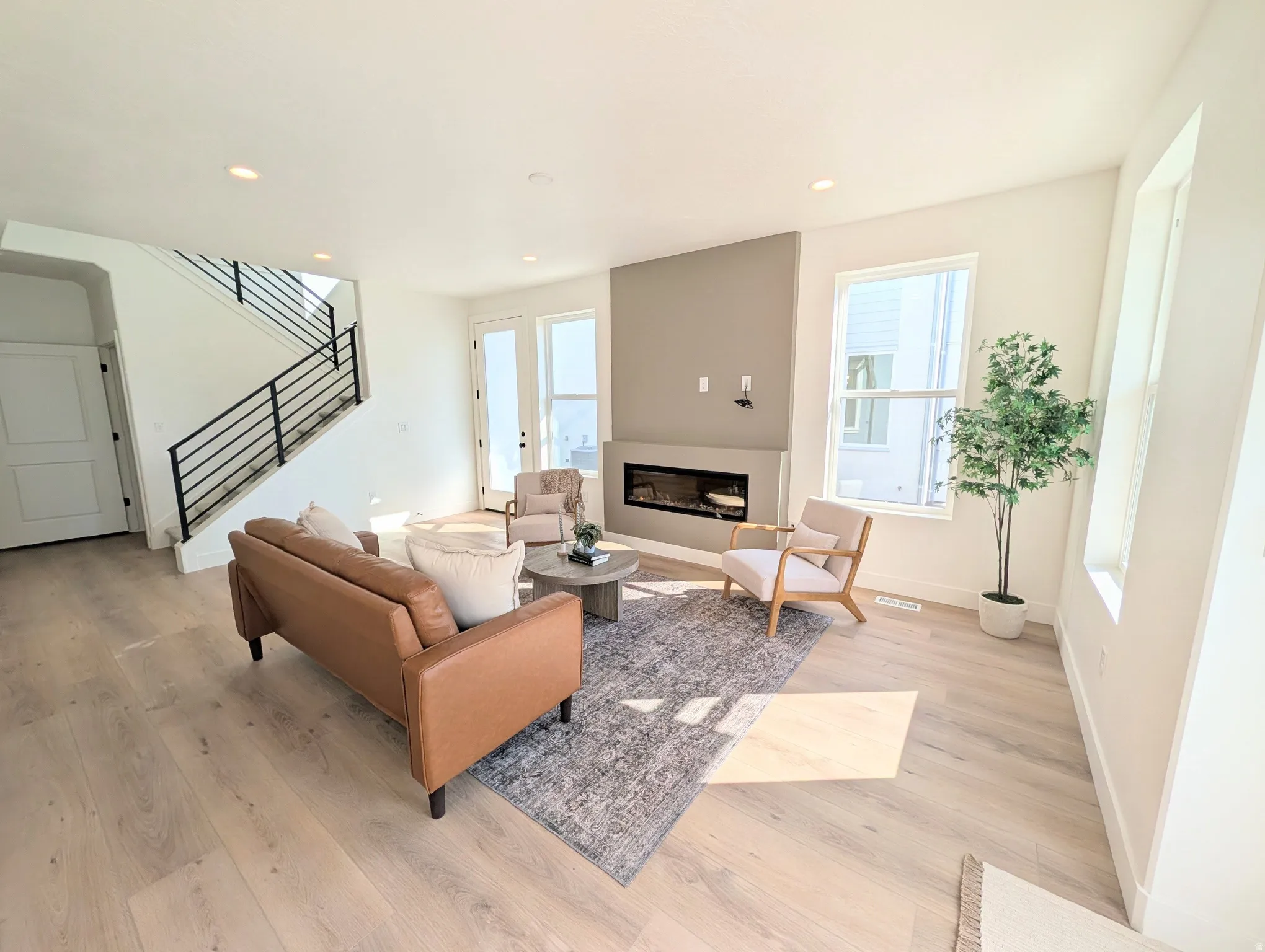 Open-concept living space with light wood-finish flooring, a contemporary linear fireplace, and recessed lighting