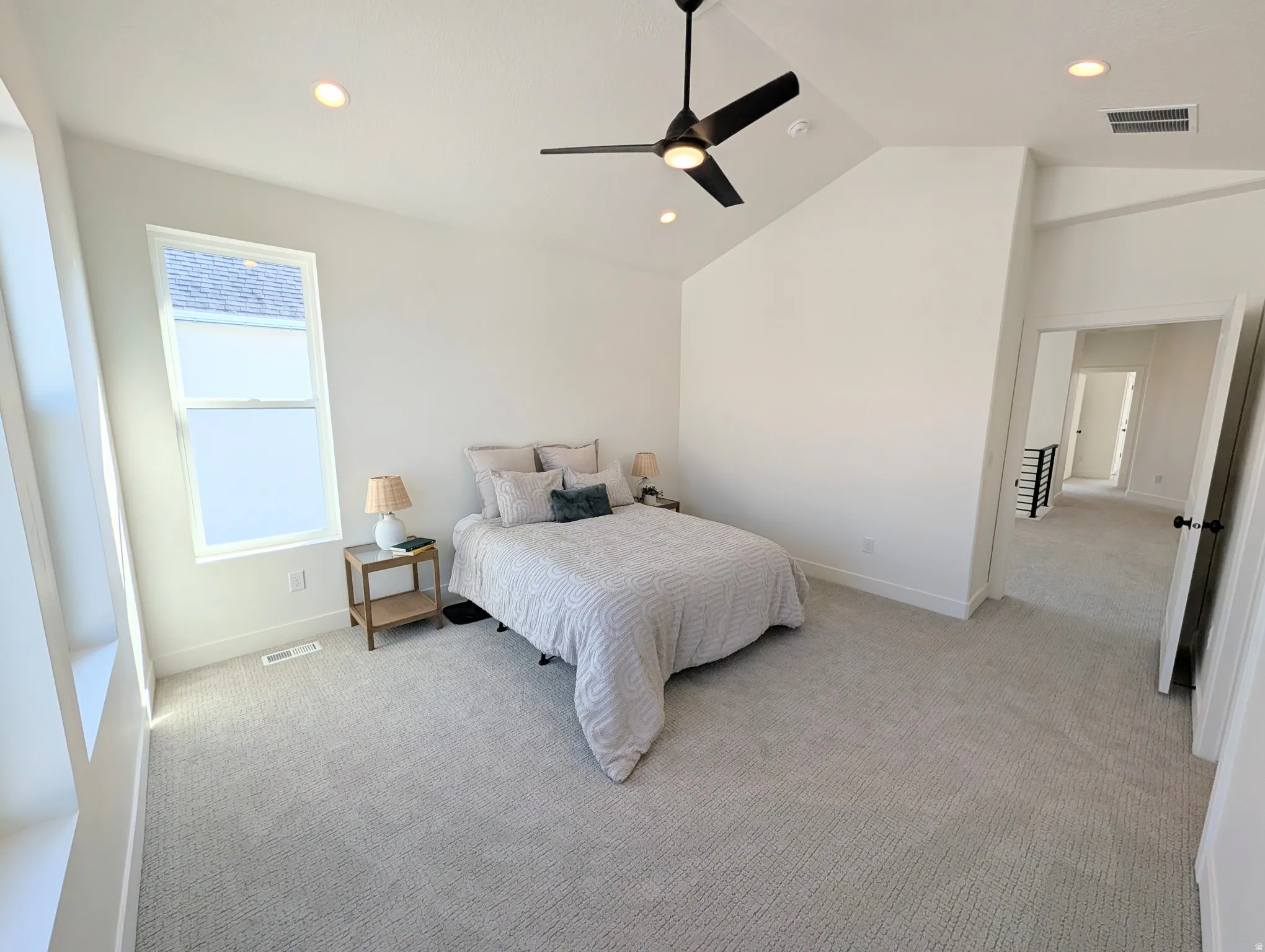 Primary bedroom with Vaulted ceiling with recessed lighting, ceiling fan, carpeted flooring, and a large window