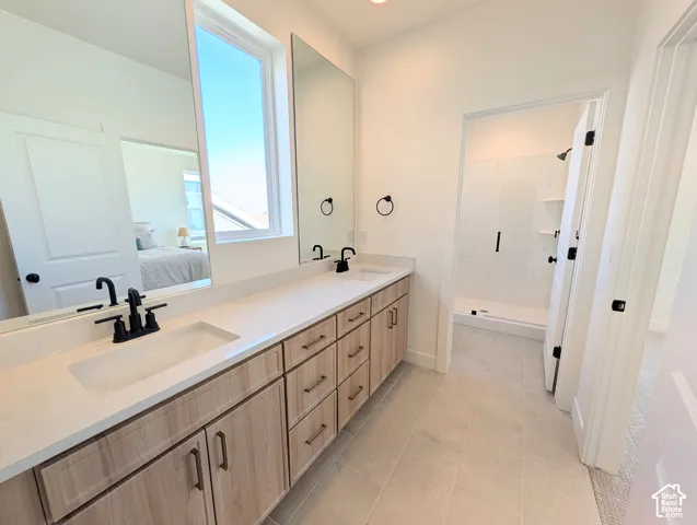 Dual vanity with undermount sinks, light wood-finish cabinetry, and matte black fixtures