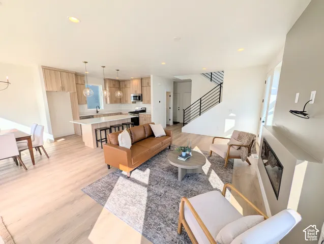 Open-concept living space with wood-finish flooring, a contemporary fireplace, and a kitchen featuring a central island with bar seating