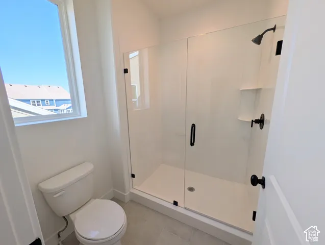 Shower enclosure with clear glass door, matte black hardware, and an integrated shelf