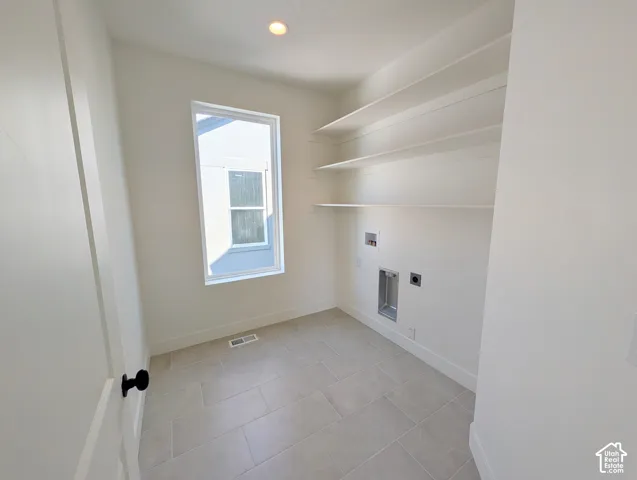 Built-in shelving, recessed lighting, rectangular window, tile flooring, and a door with black hardware