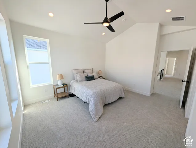 Primary bedroom with Vaulted ceiling with recessed lighting, ceiling fan, carpeted flooring, and a large window