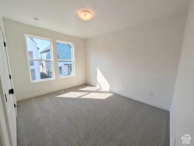 Neutral wall paint, two large windows, flush mount ceiling light, and textured carpet flooring