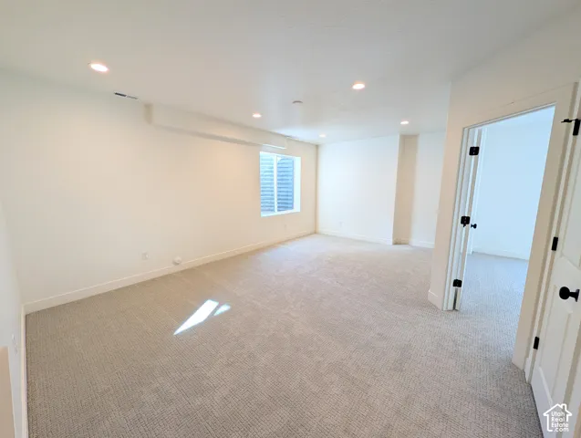 Spacious room with recessed lighting, light-toned carpeting, and white interior doors with black hardware