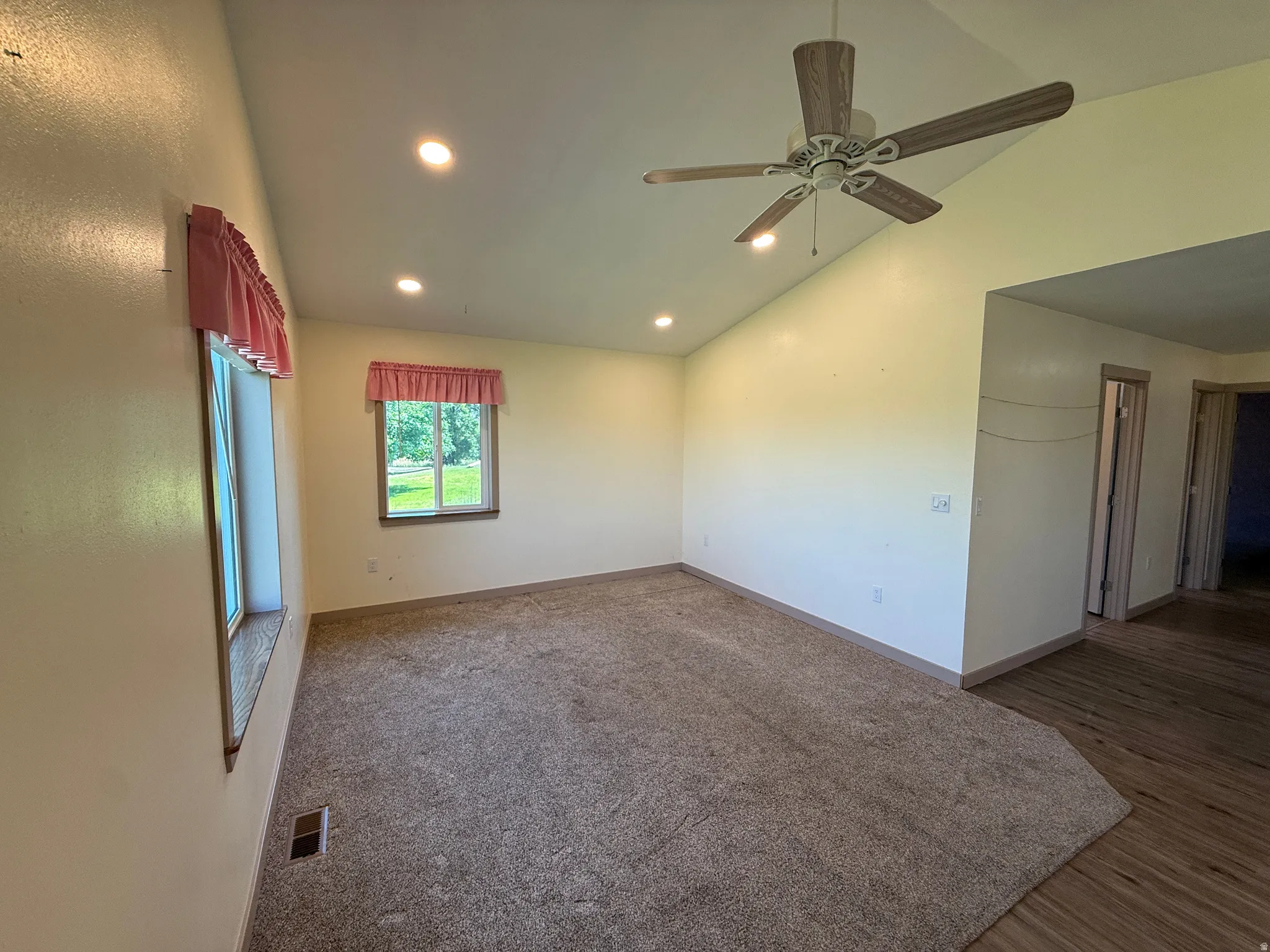 Spacious room featuring vaulted ceilings, recessed lighting, and a ceiling fan