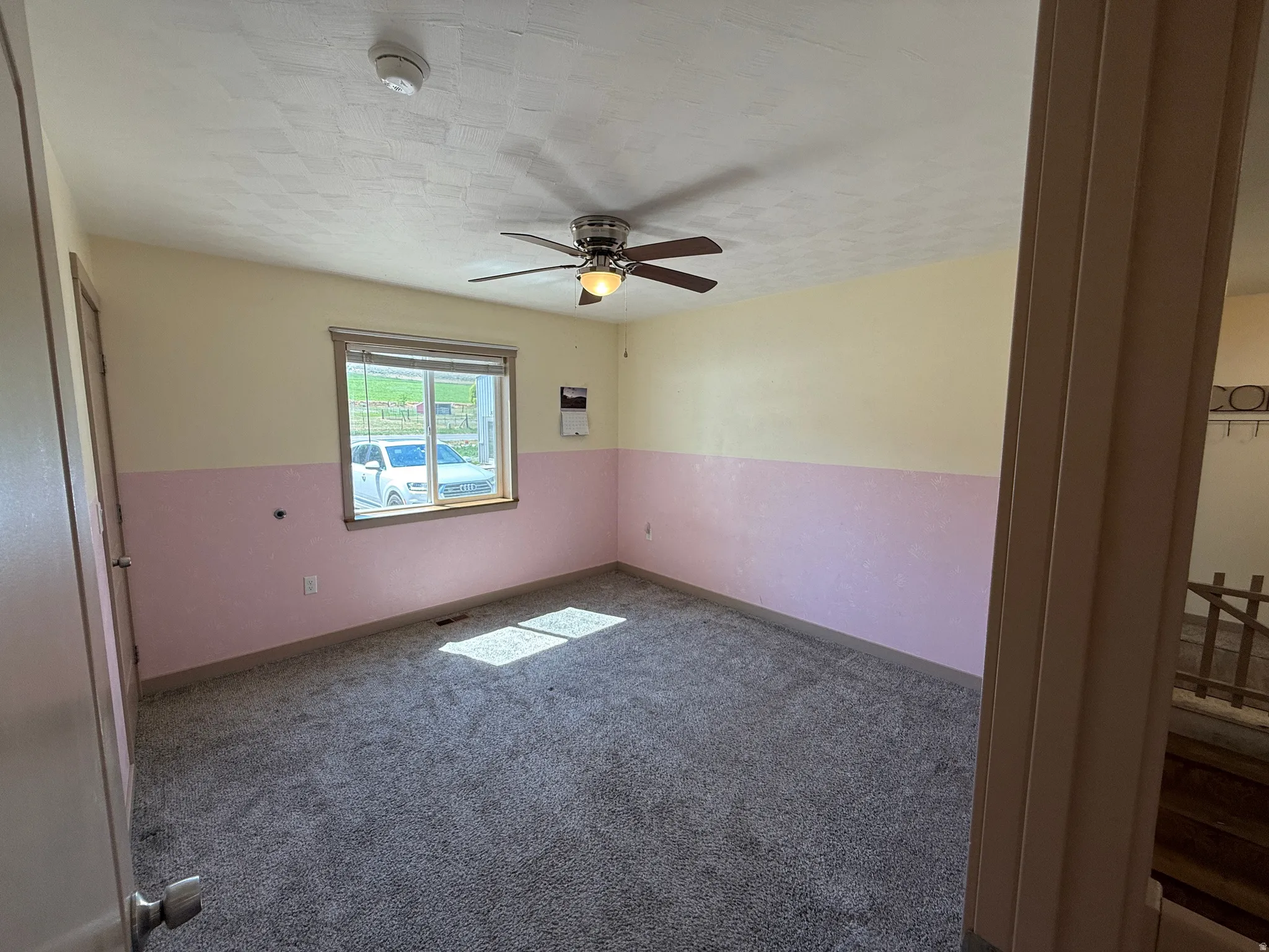 Interior room featuring gray carpeting, a multi-pane window with blinds, and a ceiling fan with integrated lighting