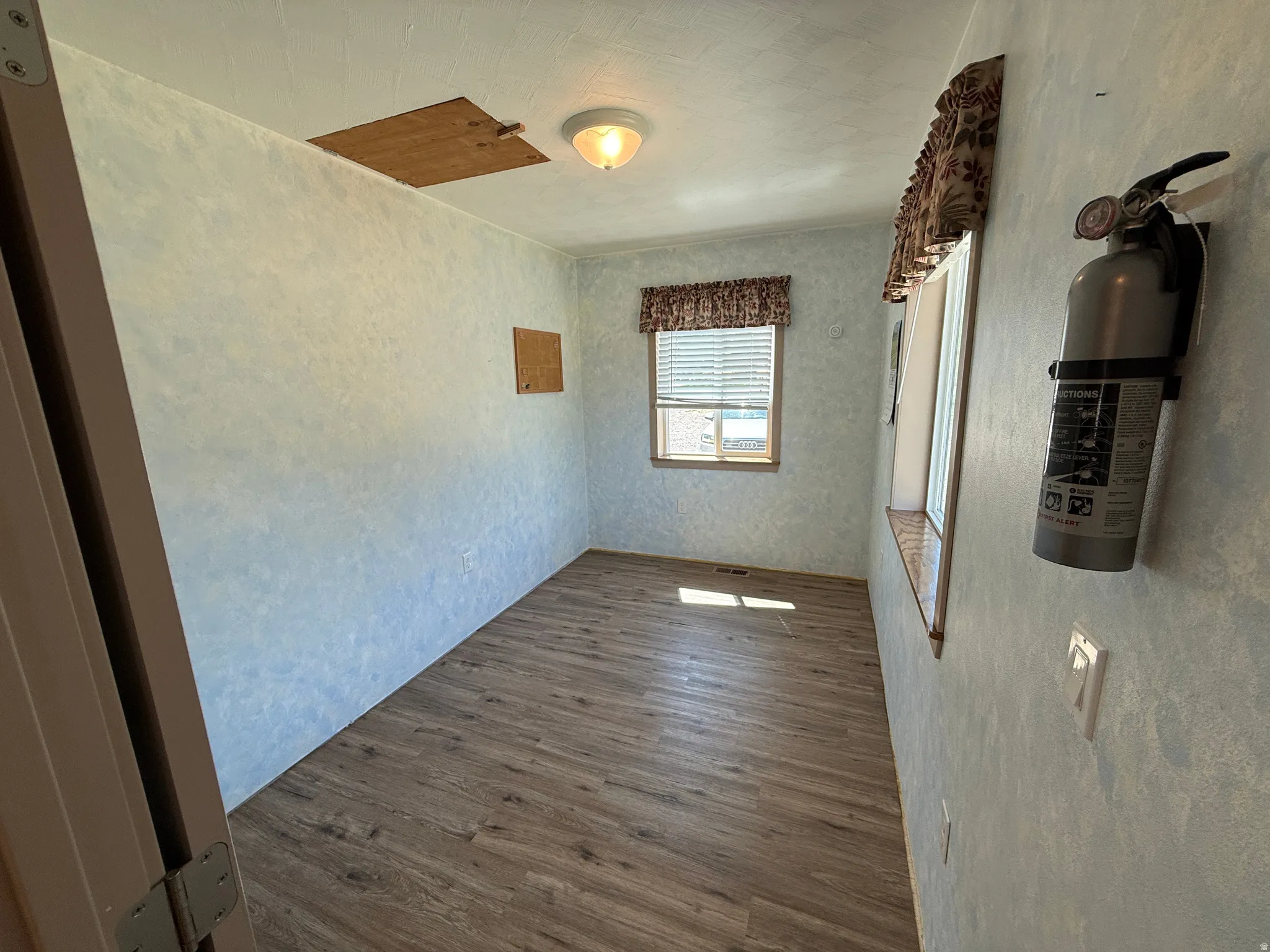 Room with wood-finish flooring, two windows, and textured wall finish