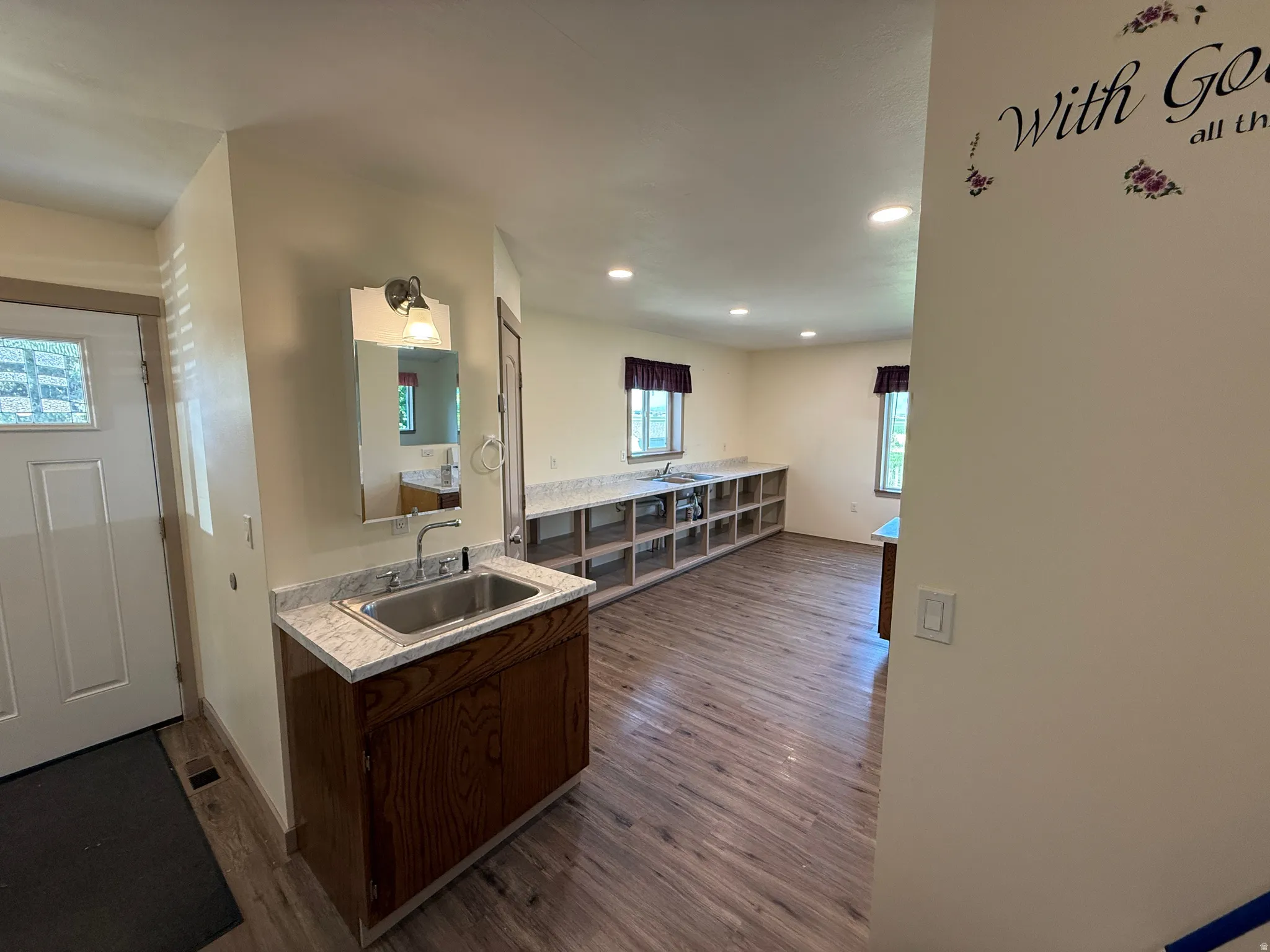 Entryway with wood-finish flooring and a built-in vanity featuring a stainless steel sink and a light-colored countertop