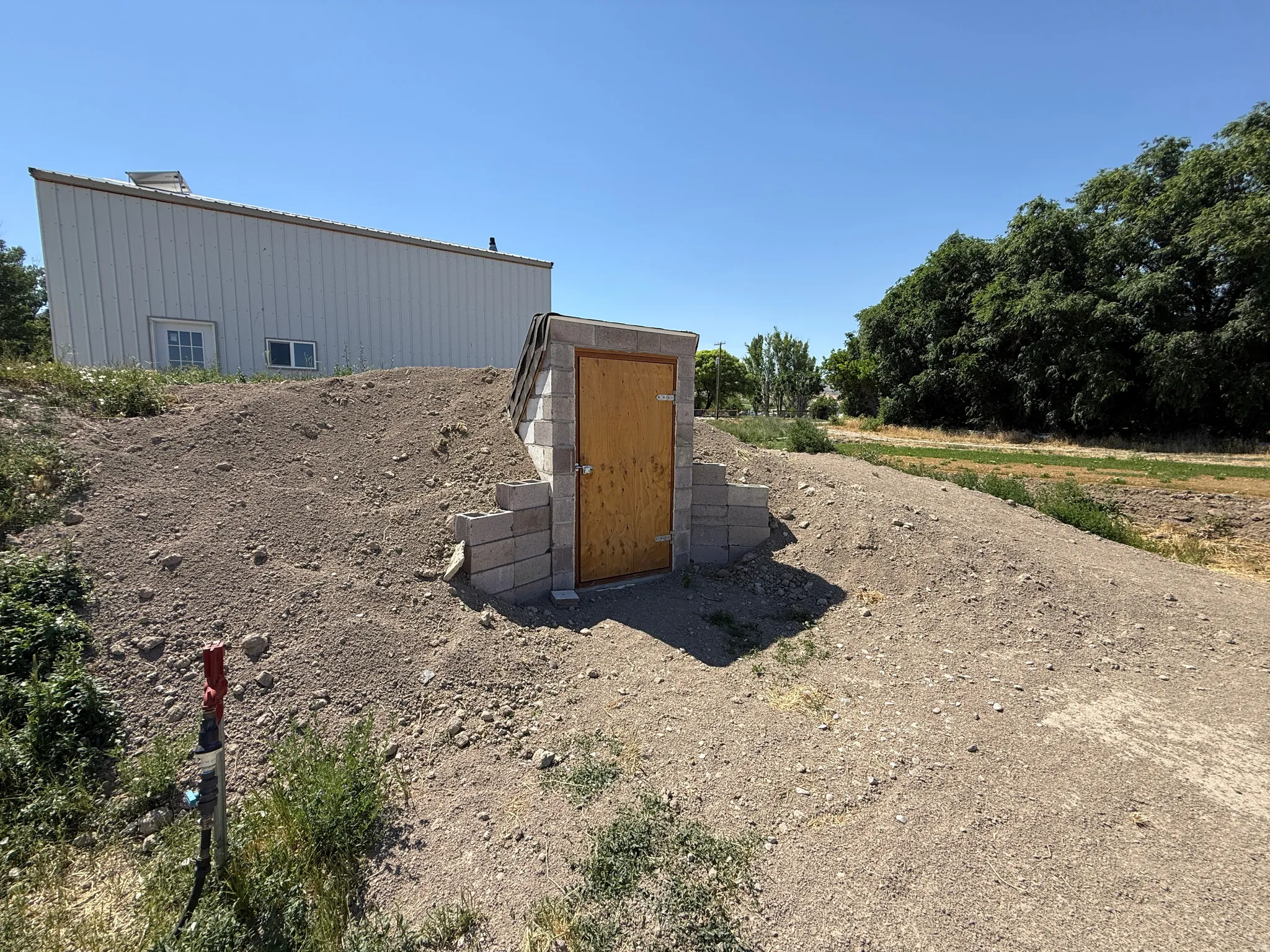 Earthen bunker featuring a wooden door, concrete block retaining walls, and surrounding natural terrain