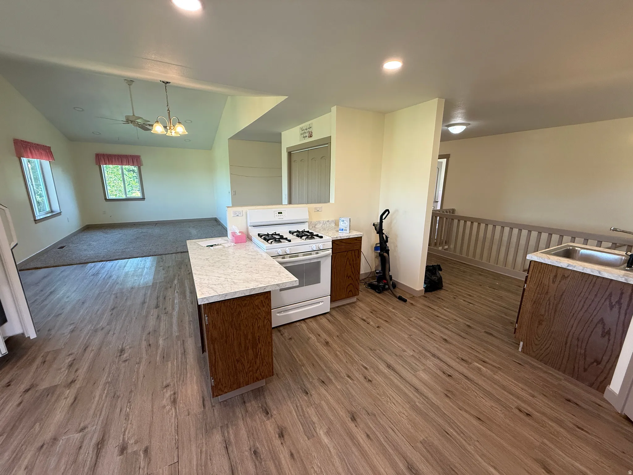 Open concept kitchen and living area featuring wood-finish flooring, white appliances, and a kitchen island with a light-colored countertop