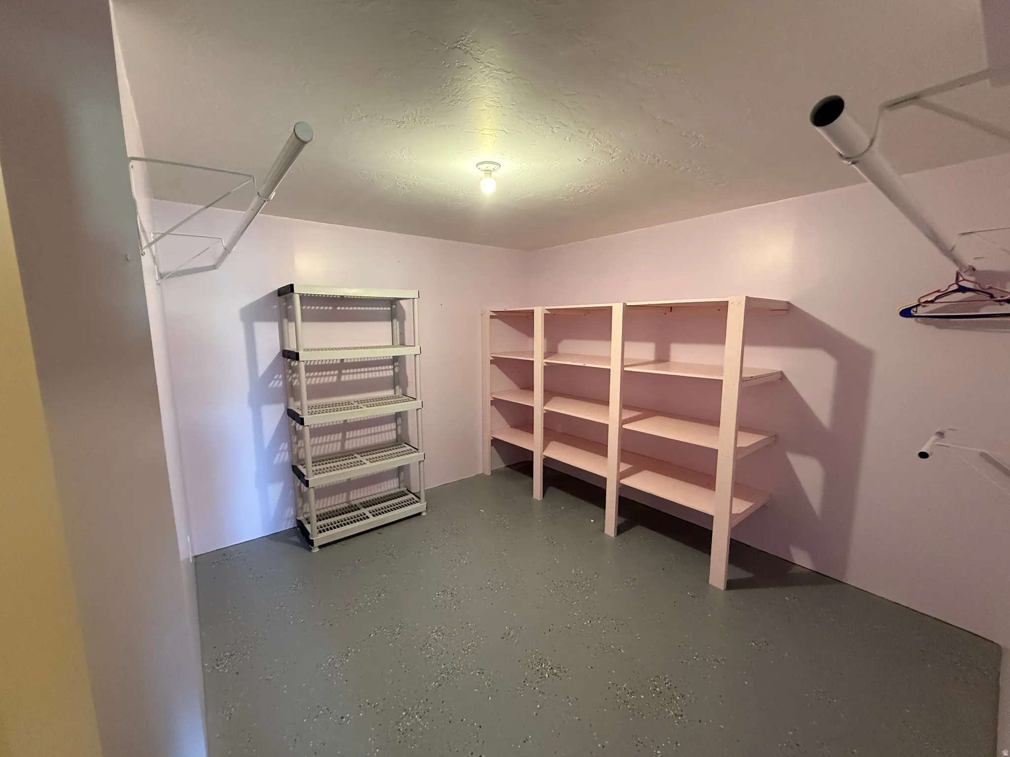 Spacious storage area featuring built-in shelving, additional shelving units, and overhead lighting