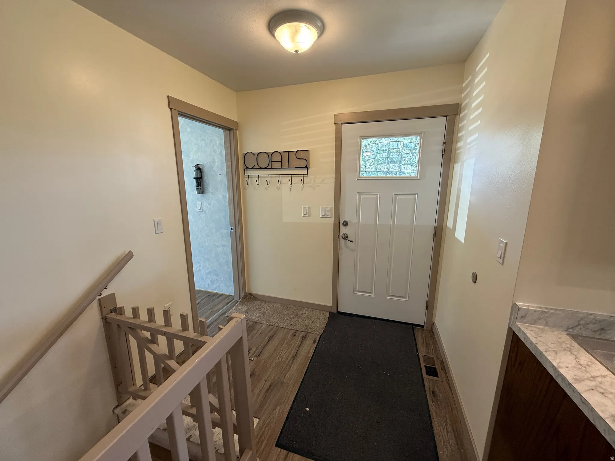 Entryway featuring wood-finish flooring and a white front door with decorative glass inserts