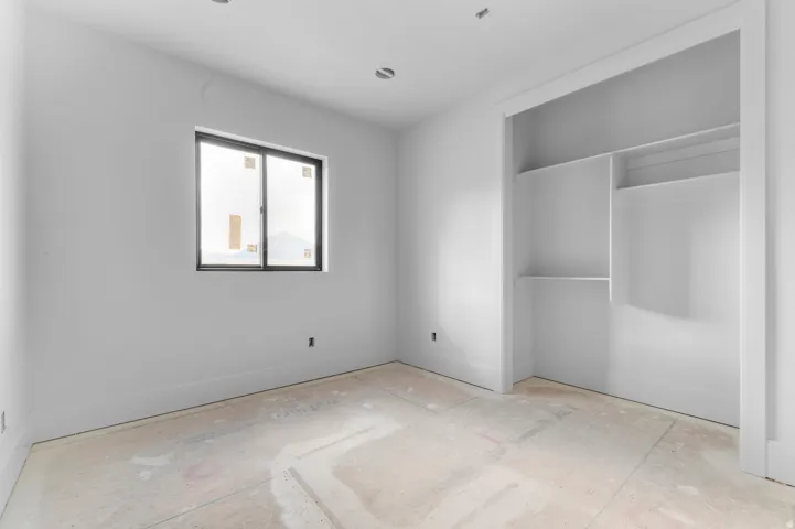 Recessed ceiling lighting, a window with dark framing, and a built-in closet with shelving and hanging rod