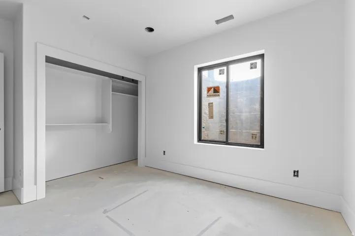 Recessed lighting, built-in closet shelving, window with dark trim, white wall finishes, and white trim