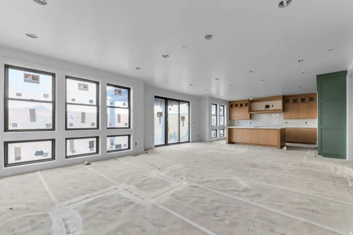 Open-concept room featuring a kitchen with wood-finish cabinetry, a large island, and a tiled backsplash