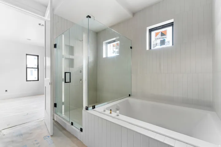 Glass-enclosed shower with black hardware, built-in recessed shelving, and vertical tile surround