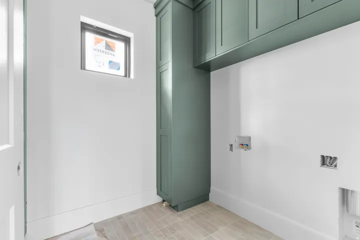 White walls, sage green cabinetry, tiled flooring, and a single window