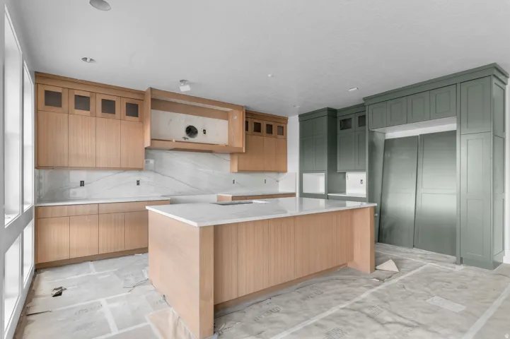 Kitchen featuring a central island, light wood-finish cabinetry, white countertops, built-in panel-ready refrigeration, and green-painted cabinetry