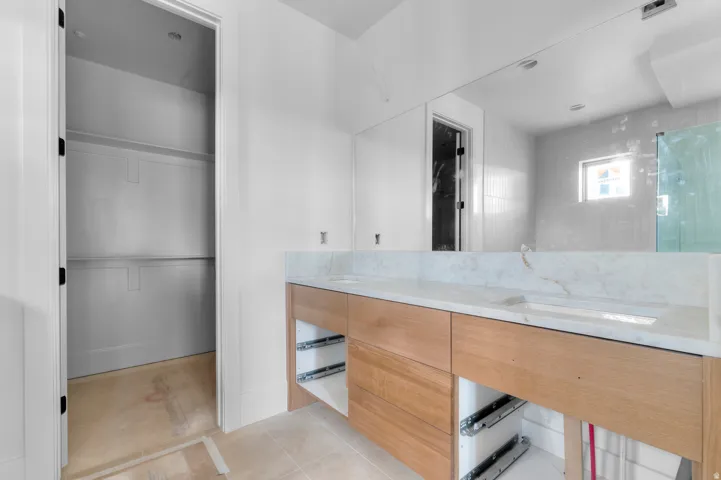 Double vanity with integrated sinks, light-toned stone countertop, and wood-finish cabinetry