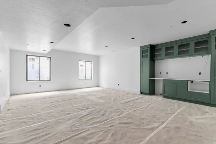 Built-in cabinetry with glass-front uppers, recessed lighting, and two windows allowing for natural light