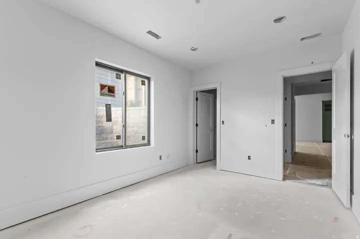Expansive room featuring multiple doorways, a large window, and recessed ceiling lighting