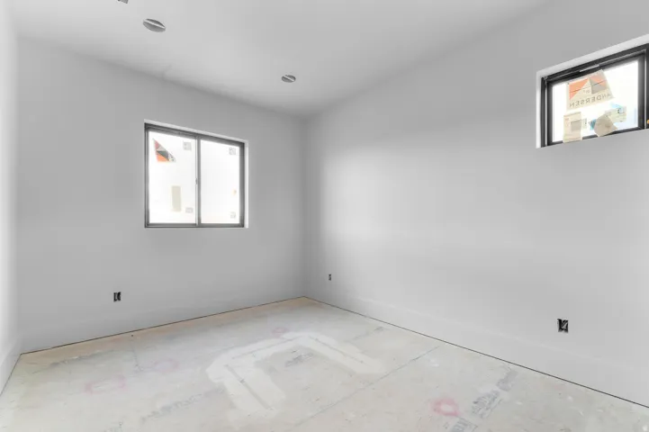 Recessed ceiling lighting, light gray wall finishes, dual windows, and unfinished flooring