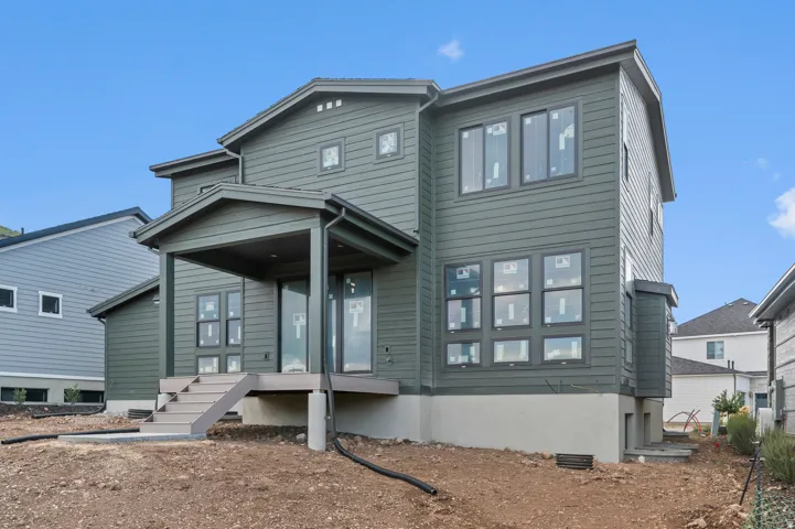 Two-story exterior with horizontal siding, covered porch, multiple windows, and a raised foundation