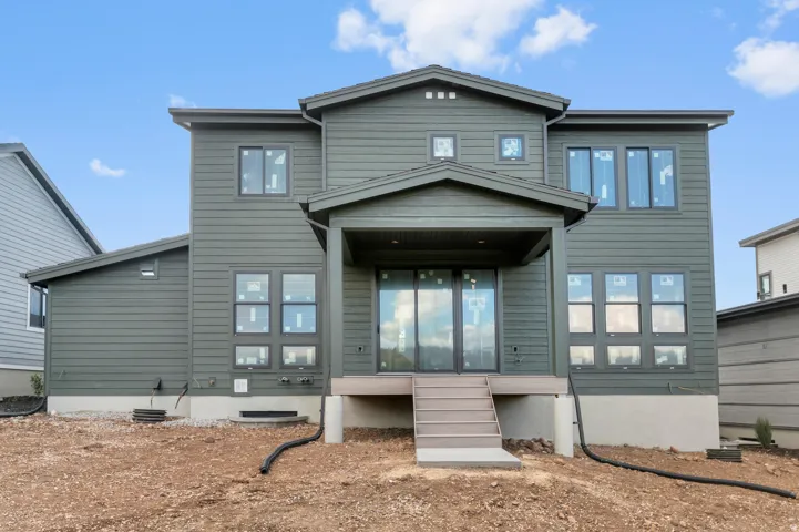 Two-story exterior with horizontal siding, covered patio, multiple windows, and a multi-level deck