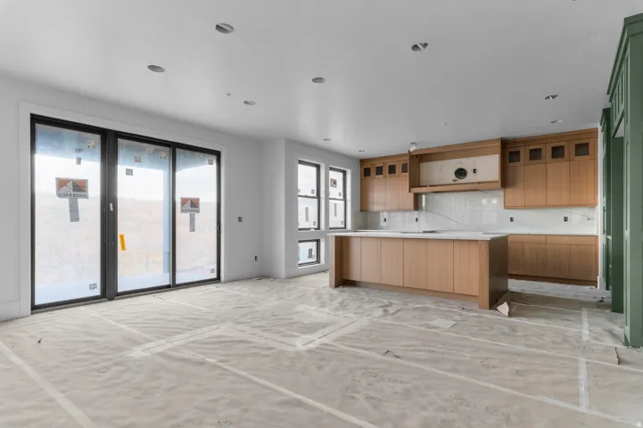 Kitchen featuring wood-finish cabinetry, a large center island, and a full tile backsplash