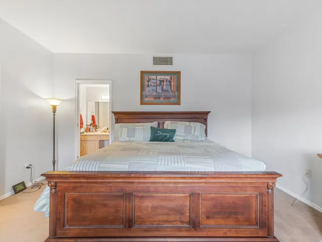 Bedroom featuring neutral wall paint, light-toned carpet, and a wood-finish bed frame