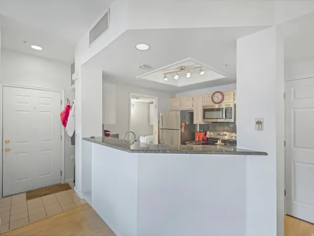 Kitchen with stainless steel appliances, light wood-finish cabinetry, and a dark stone countertop peninsula