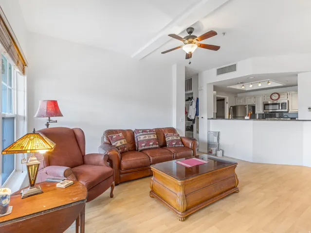 Spacious living area featuring wood-finish flooring, a vaulted ceiling, and an integrated ceiling fan