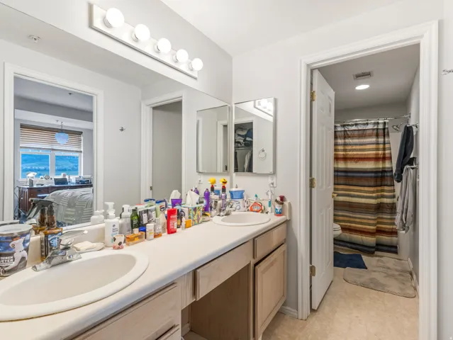 Bathroom featuring a dual-sink vanity with ample counter space, wood-finish cabinetry, and an overhead vanity light fixture