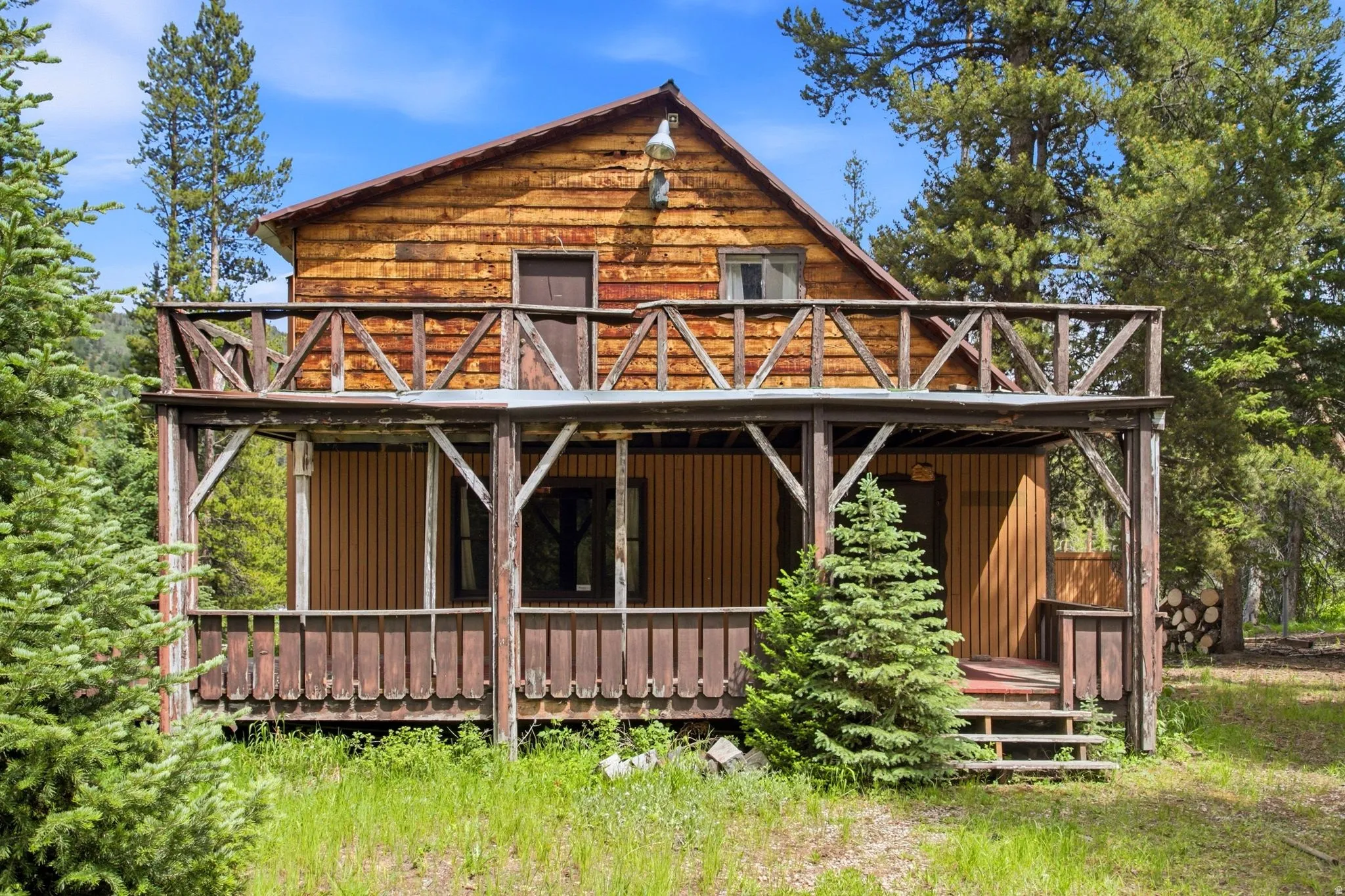 Rustic wood-sided exterior featuring a covered porch, upper balcony, exposed wood rafter tails, and a sloped roofline