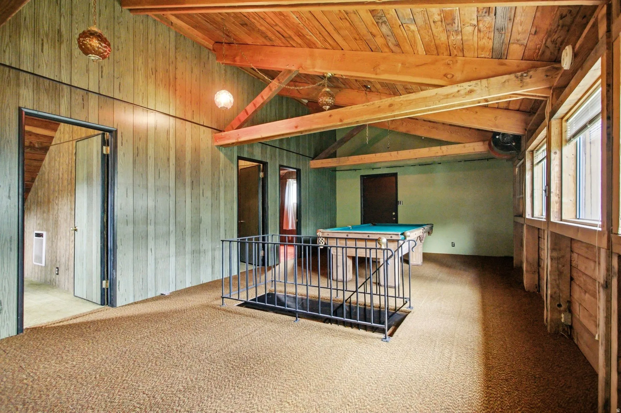 Spacious recreation area featuring exposed wood beam ceilings and wood-finish wall paneling