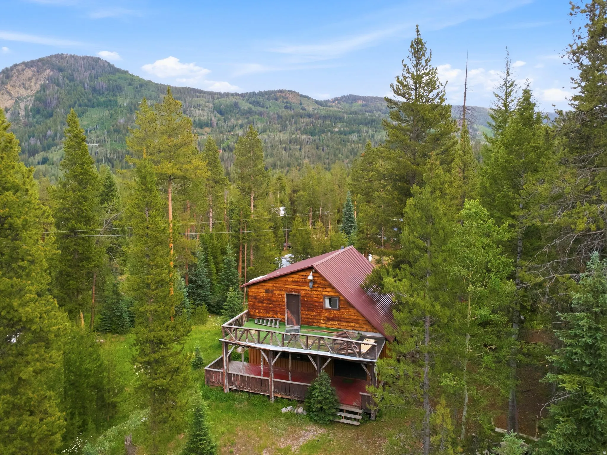 Wood-sided cabin featuring a red metal roof and multiple outdoor deck spaces
