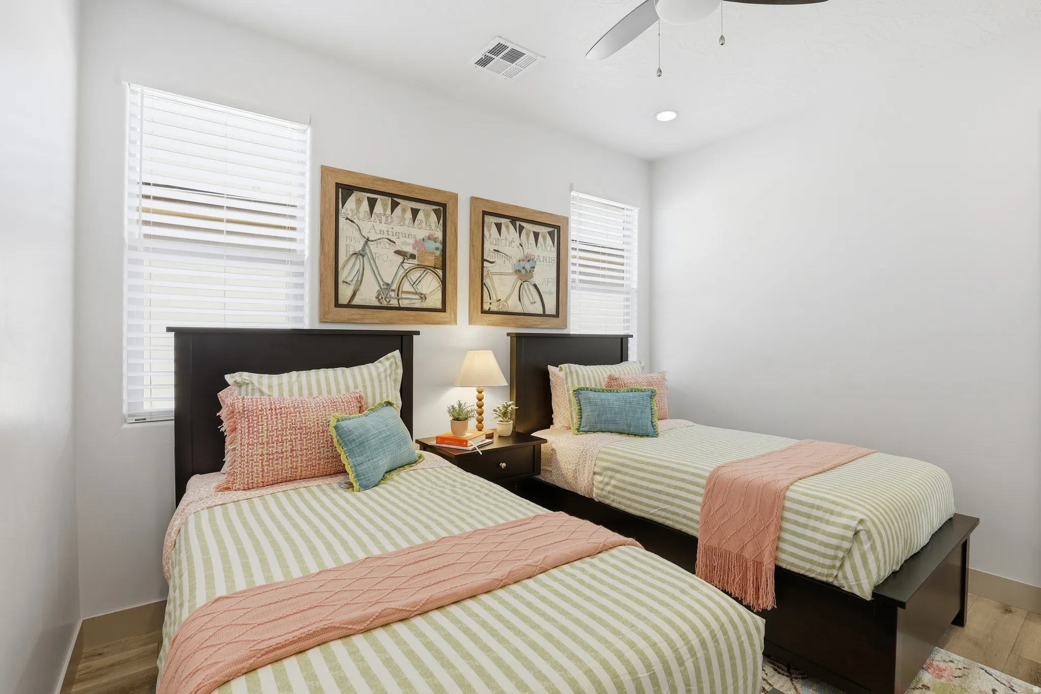 Spacious bedroom featuring light-colored walls, wood-finish flooring, a contemporary ceiling fan, and recessed lighting