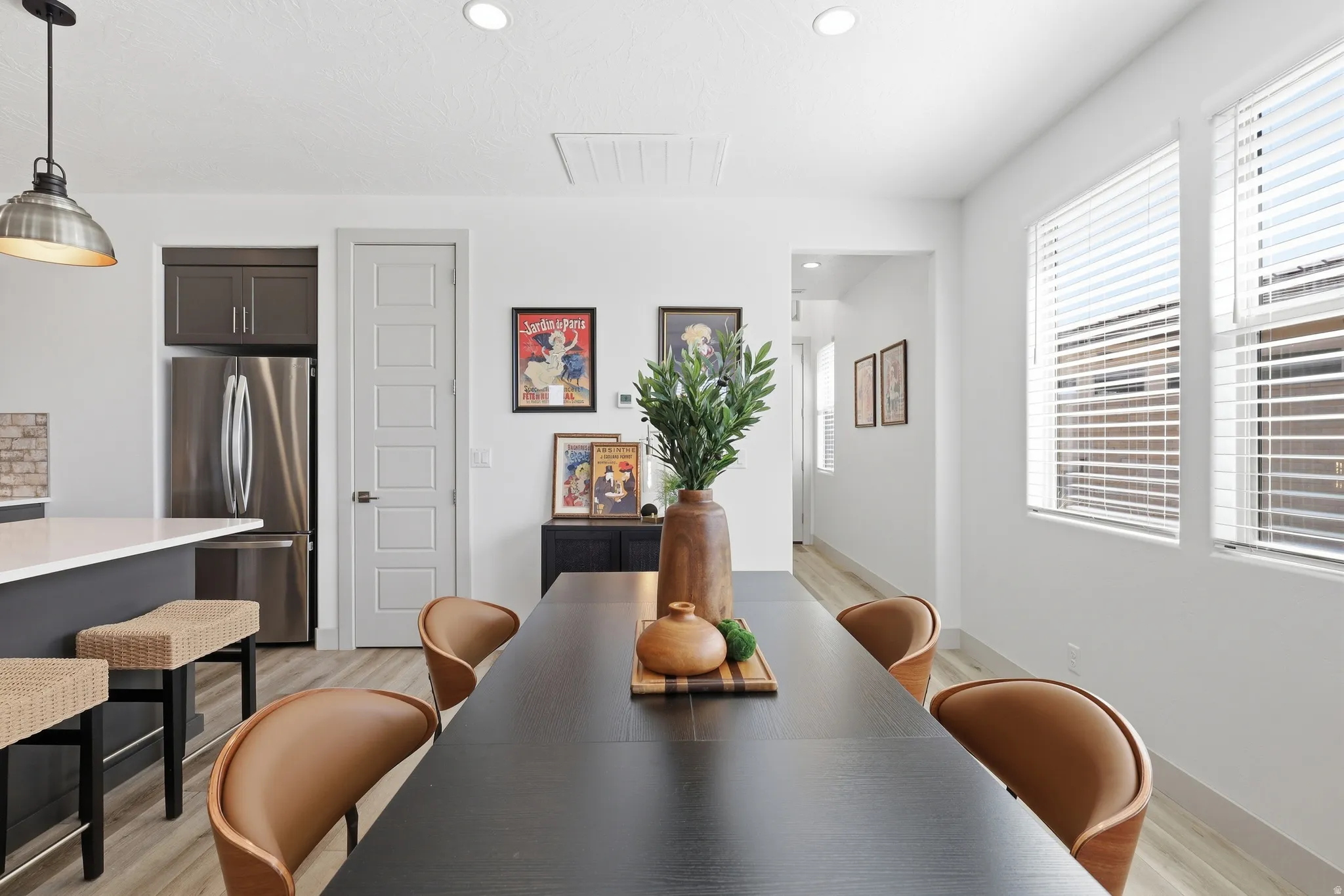 Open-concept dining area featuring wood-finish flooring, recessed lighting, and a modern pendant light fixture