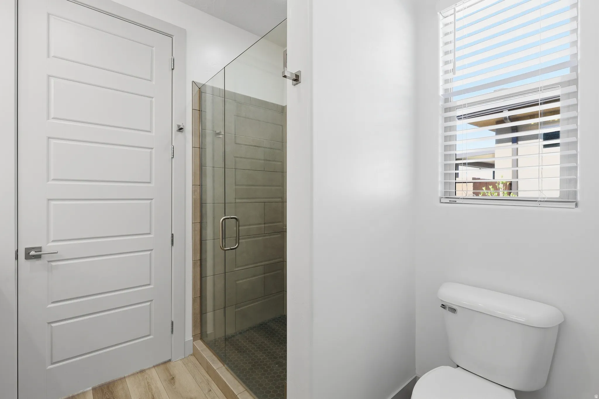 Glass-enclosed shower with horizontal tile surround and dark hex-tile flooring