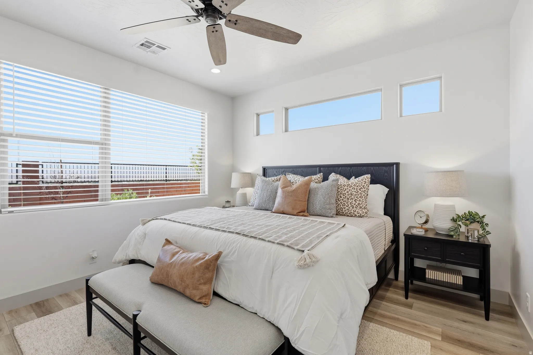 Light wood-finish flooring complements the white walls and ceiling fan