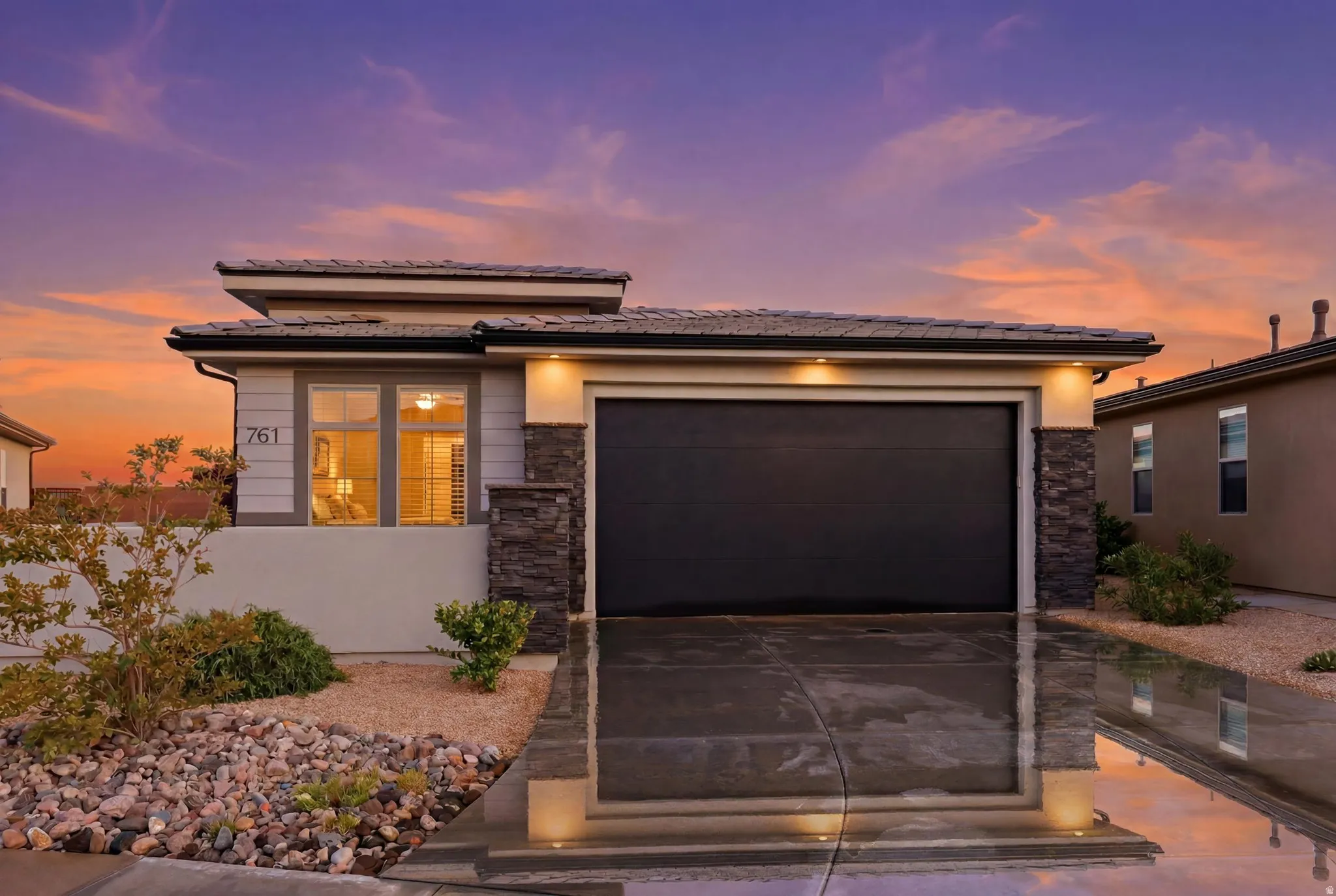 Contemporary exterior featuring a dark garage door, stone accents, and stucco siding