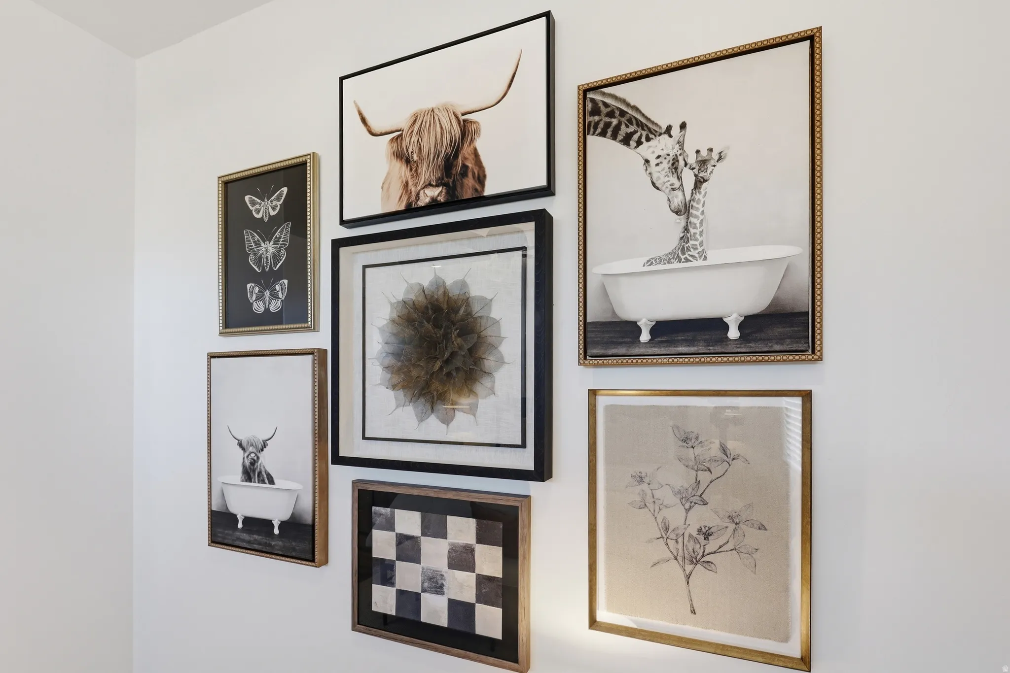 White wall with a gallery display of framed artwork, featuring varied frame styles and sizes