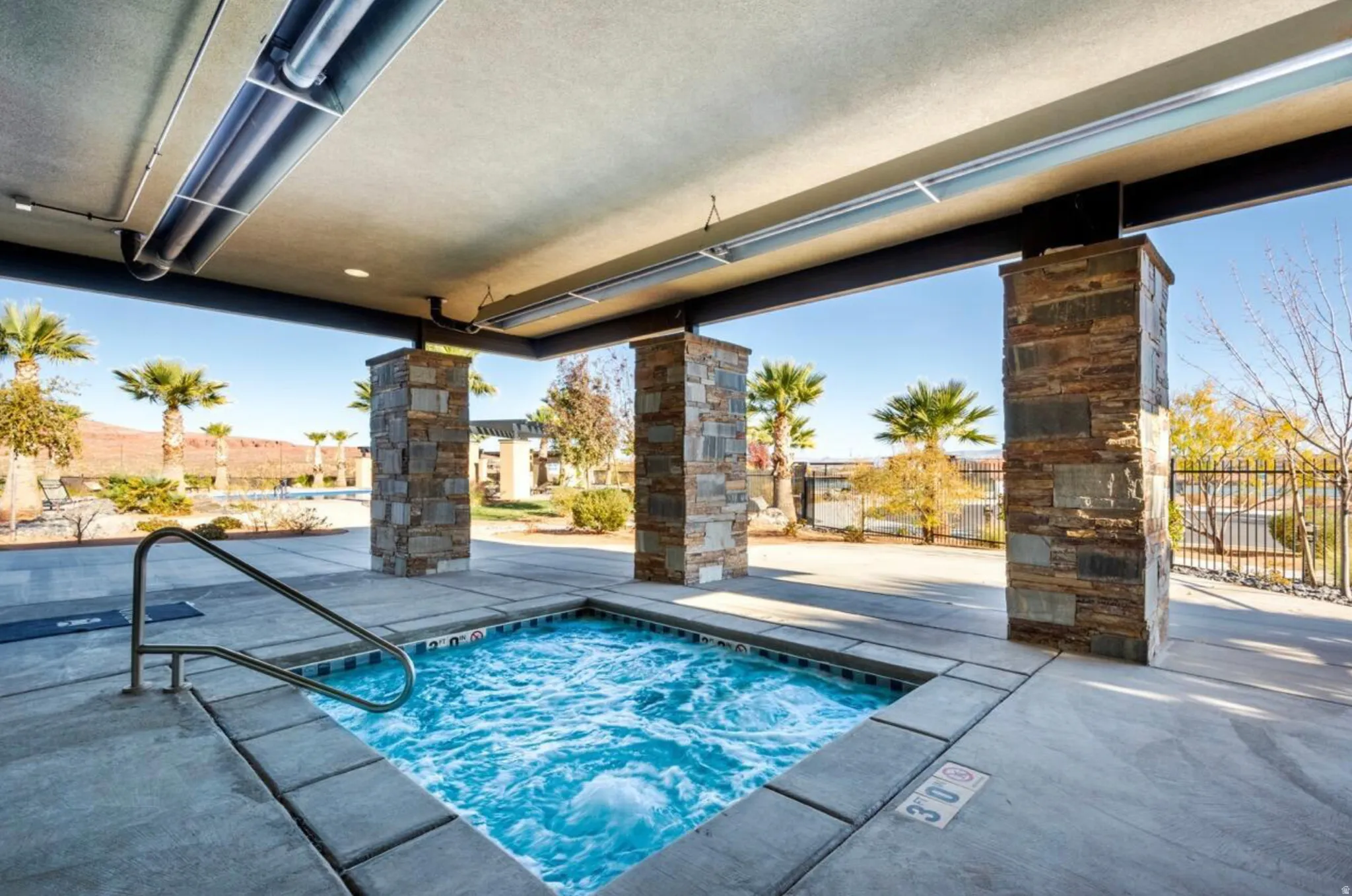 Covered hot tub with concrete surround and a stainless steel grab rail