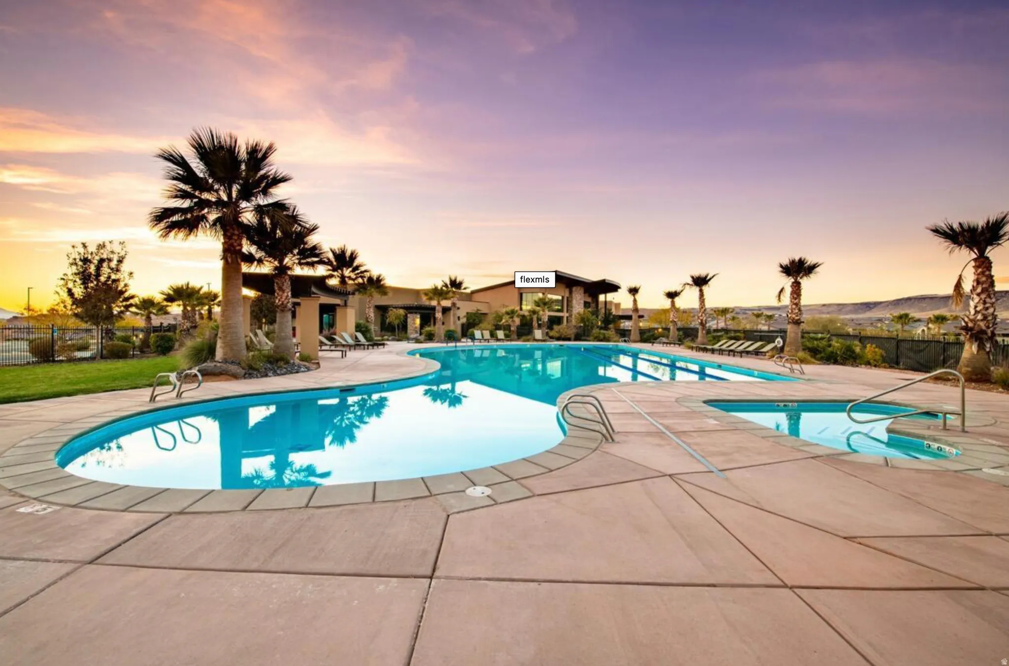 Resort-style pool area featuring a freeform swimming pool, integrated spa, and expansive concrete decking