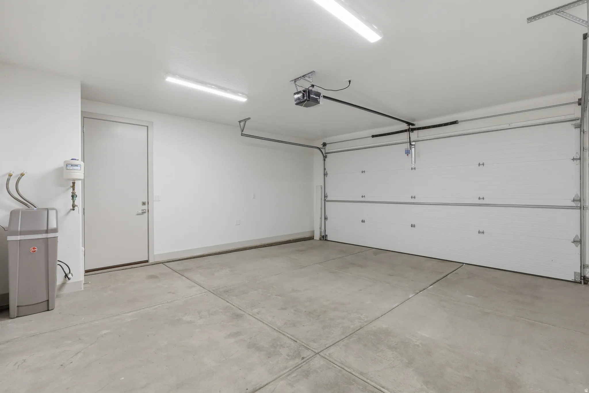 Spacious garage featuring a concrete floor, overhead lighting, and an automatic garage door opener