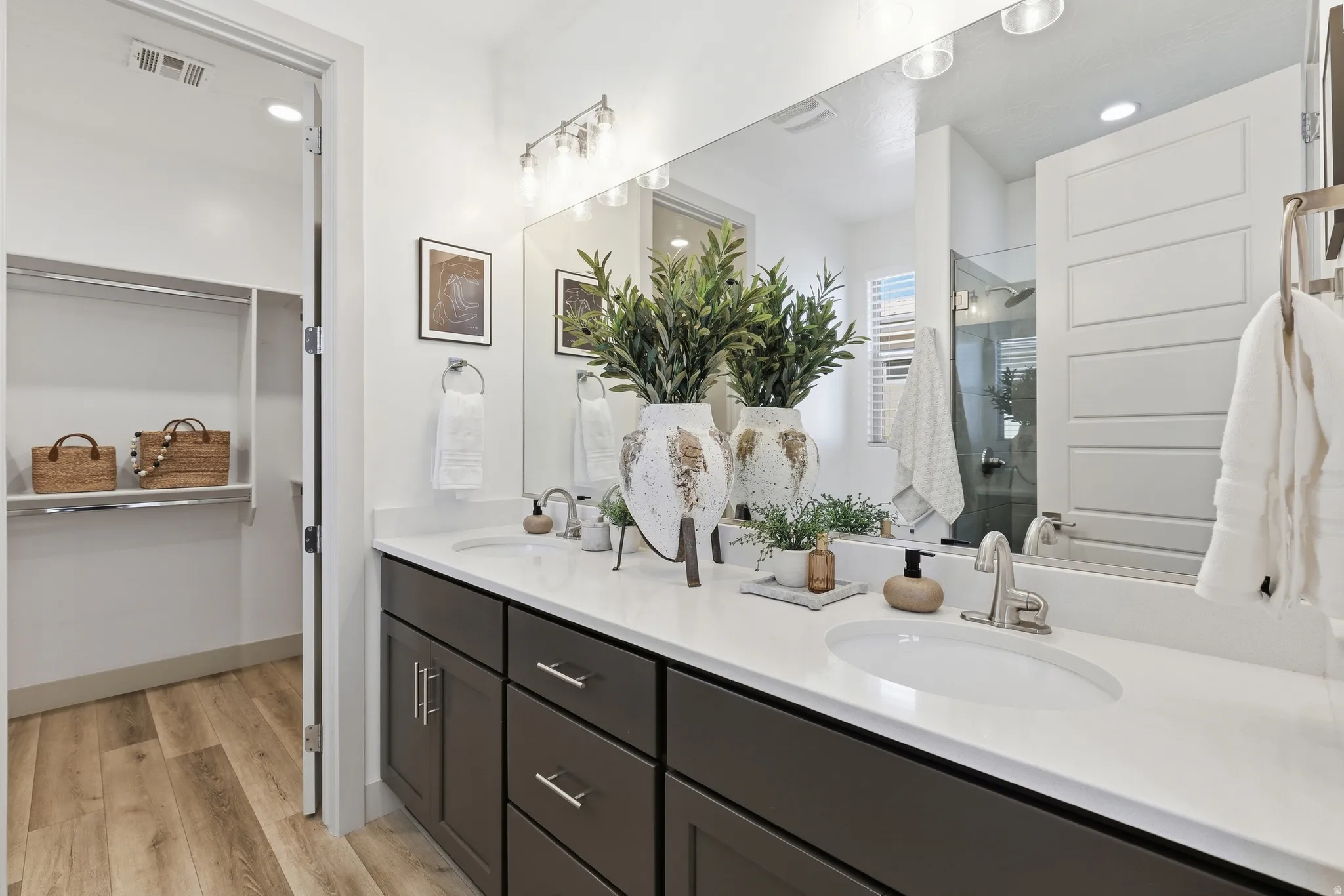 Dual vanity with white undermount sinks and brushed nickel faucets, set in a white countertop over dark wood cabinetry