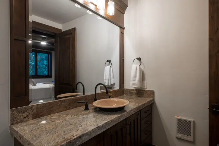 Bathroom vanity featuring a stone-finish countertop, a bowl sink, and a wall-mounted faucet